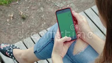 美丽的女孩手里拿着黑色的智能手机，手里拿着绿色的屏幕，手里拿着手机智能手机。